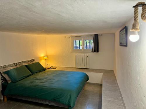 a bedroom with a green bed and a window at Les 2 Oliviers in Caromb