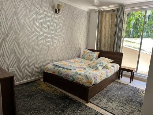a bedroom with a bed in a room with a window at Masaki - 2 Bedroom Apartment in Dar es Salaam