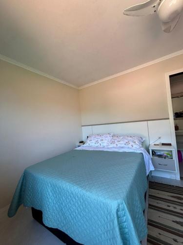 ein Schlafzimmer mit einem Bett mit einer blauen Decke in der Unterkunft Suíte privativa - Praia do Canto Grande, Bombinhas in Bombinhas