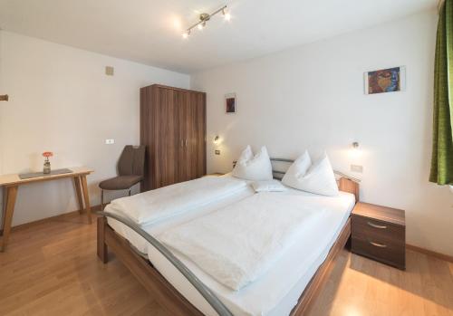 a bedroom with a large white bed with a desk at Residence Ortlerhof in Prato allo Stelvio