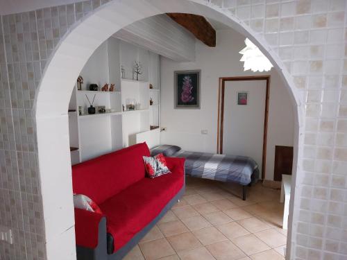 a living room with a red couch and a bed at Confortevole Appartamento Il Sorriso piano terra ingresso e parcheggio indipendente per una tranquilla privacy in Lugo
