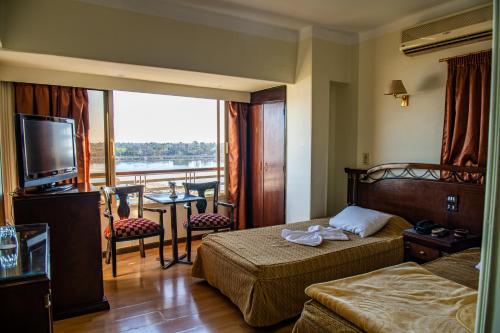 a hotel room with two beds and a balcony at Assiutel in Asyut