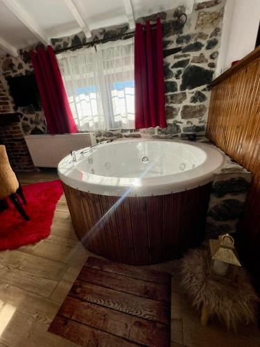a large bath tub in a room with red curtains at Patriko Mountain Chalet in Palaios Agios Athanasios