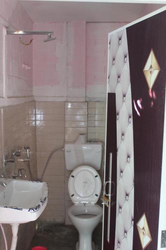 a bathroom with a white toilet and a sink at Changmai's Inn kaziranga in Kāziranga