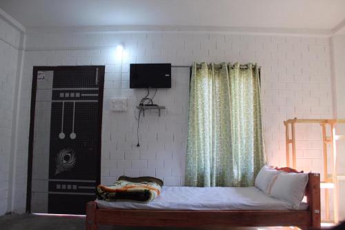 a bedroom with a bed and a tv on the wall at Changmai's Inn kaziranga in Kāziranga