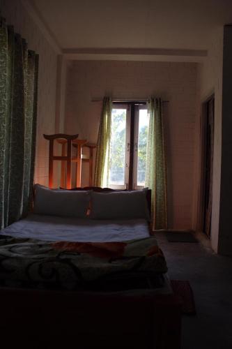 Bett in einem Zimmer mit Fenster in der Unterkunft Changmai's Inn kaziranga in Kāziranga