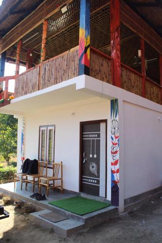 ein Gebäude mit einem Balkon und einer Bank davor in der Unterkunft Changmai's Inn kaziranga in Kāziranga