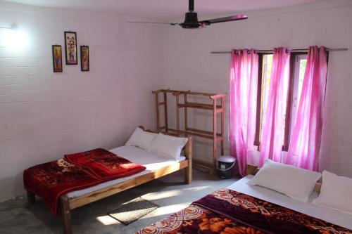 two beds in a room with pink curtains at Changmai's Inn kaziranga in Kāziranga