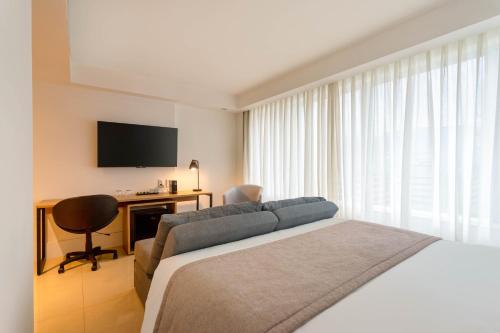 a bedroom with a bed and a desk and a television at Tryp by Wyndham Brasília Nações in Brasilia