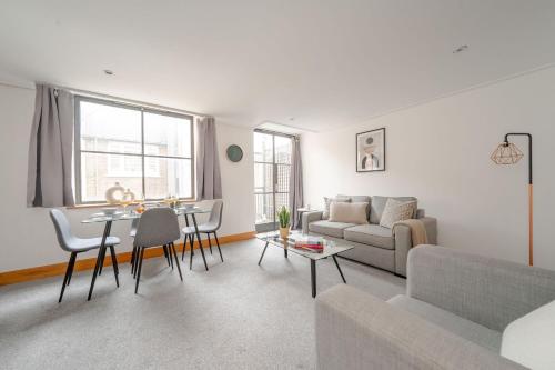 ein Wohnzimmer mit einem Sofa und einem Tisch in der Unterkunft Holborn - 2BR Near Covent Garden -CityApartmentStay in London
