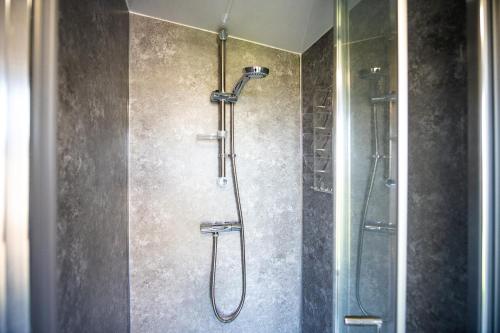 W łazience znajduje się prysznic ze szklanymi drzwiami. w obiekcie The Other Red Hut w mieście Rye Harbour