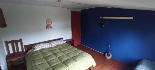 1 dormitorio con cama y pared azul en Dónde la Señora Haydée, en Chonchi