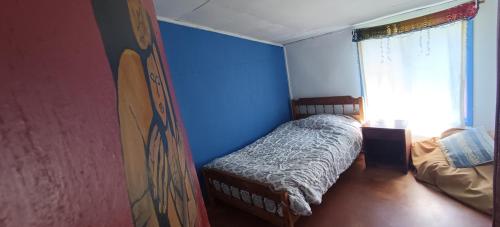 1 dormitorio con 1 cama con pared azul en Dónde la Señora Haydée, en Chonchi