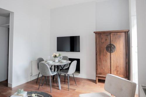 a dining room with a table and chairs and a tv at Stylish Flat in the heart of South Kensington in London
