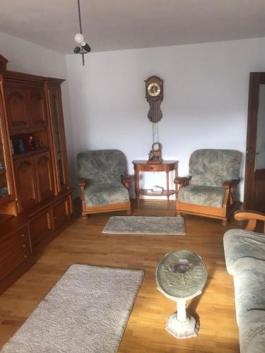 a living room with two chairs and a table and a clock at Vila Ana Ipatescu in Craiova