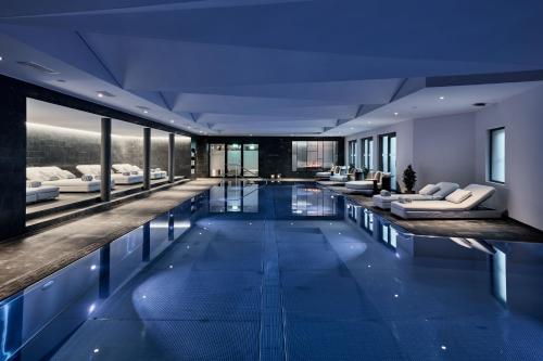 a large swimming pool with couches and chairs in a building at Hotel GRACE LA MARGNA ST MORITZ in St. Moritz