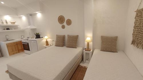 Biała sypialnia z 2 łóżkami i kuchnią w obiekcie Evdion Naxos Town w mieście Naksos