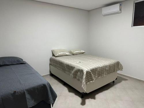 Bett in einem weißen Zimmer mit einem Bett von sidx sidx sidx sidx in der Unterkunft Apartamento com vista para palco festival in Chapada dos Guimarães