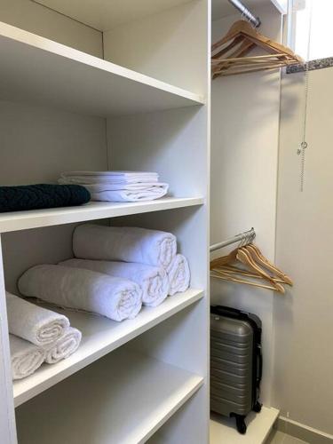 a white closet with towels and a pile of towels at Loft 116 B - Porto Belo/SC in Porto Belo