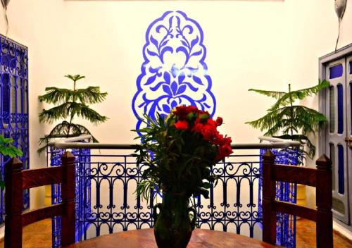 a vase with red flowers sitting on a table at RIAD DAR WINK in Marrakesh