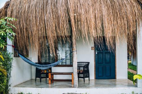a hammock in front of a house with a thatch roof at Baobab Beach Vilanculos in Vilanculos
