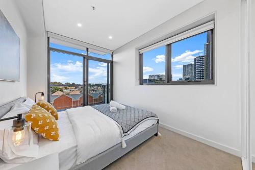 a bedroom with a bed and two windows at Entire home with parking in Parramatta in Sydney