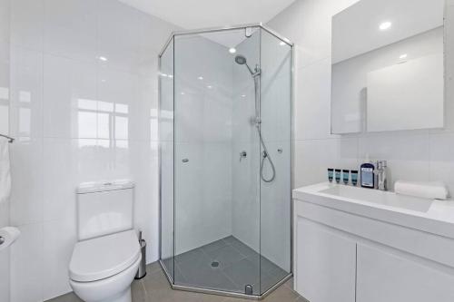 a white bathroom with a shower and a toilet at Entire home with parking in Parramatta in Sydney