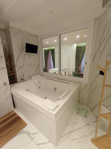 a white bathroom with a tub and a large mirror at Babylon Luxury Suite & Apartments in Naples