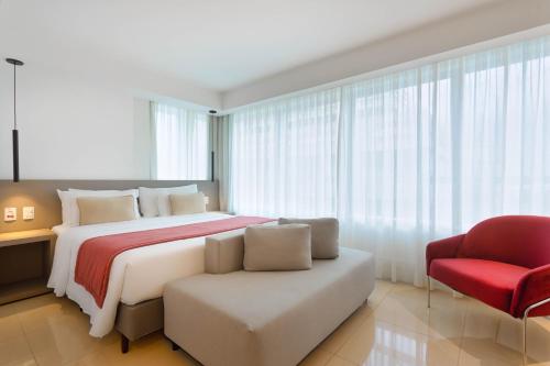a bedroom with a large bed and a red chair at Ramada by Wyndham Brasilia Alvorada in Brasilia