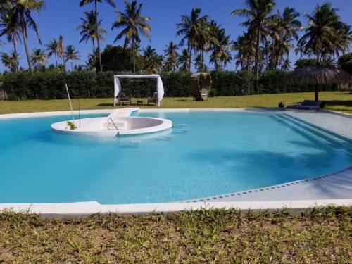 a large blue swimming pool with a boat in it at Casa Bali Tofo in Praia do Tofo