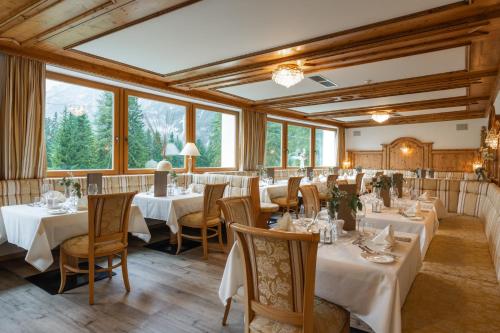 uma sala de jantar com mesas, cadeiras e janelas em Hotel Asterbel em Braies (Prags)