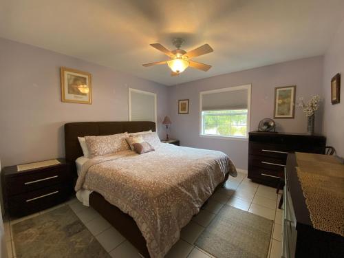 Cozy Cottage near Beaches and Downtown Sarasota في ساراسوتا: غرفة نوم بسرير ومروحة سقف