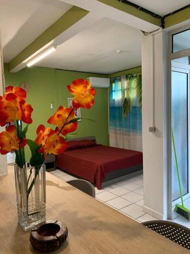 un jarrón de flores sobre una mesa en un dormitorio en Logement avec parking à proximité de l’aéroport en Les Abymes