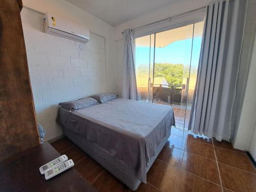 ein Schlafzimmer mit einem Bett und einem großen Fenster in der Unterkunft Lindo 2 Qts Vaga Búzios vista deslumbrante do Mar in Búzios