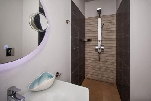 a bathroom with a shower with a sink and a mirror at Ocean Island Villa in Achlia