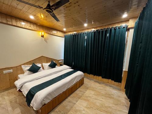a bedroom with a bed and a black curtain at Hotel Mid Orchard Kasol l River Side in Kasol