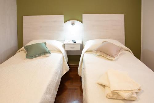 two beds with white sheets and pillows in a room at Affitti brevi GREEN HOUSE in Cascina