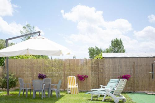 a group of chairs and an umbrella in a yard at Affitti brevi GREEN HOUSE in Cascina