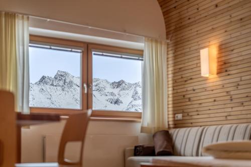 a room with a couch and a window with a mountain view at Hotel Hochsölden in Sölden
