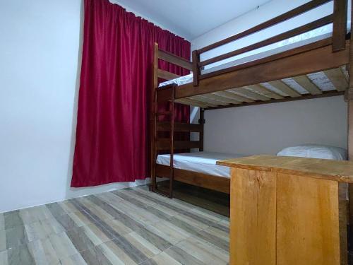 1 dormitorio con 2 literas y cortina roja en Papaturro House, en La Cruz