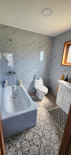 a bathroom with a tub and a toilet at Amplia Casa 6-8 personas, Sector tranquilo in Dalcahue
