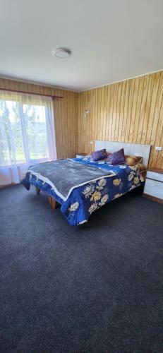 a bedroom with a bed with a blue comforter at Amplia Casa 6-8 personas, Sector tranquilo in Dalcahue