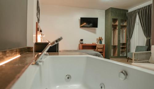 a bathroom with a bath tub and a bedroom at Hotel Sacha Golden in Otavalo
