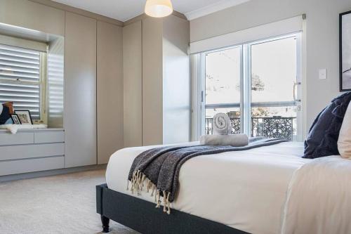 a white bedroom with a bed and a window at Charming house in Leichhardt in Sydney
