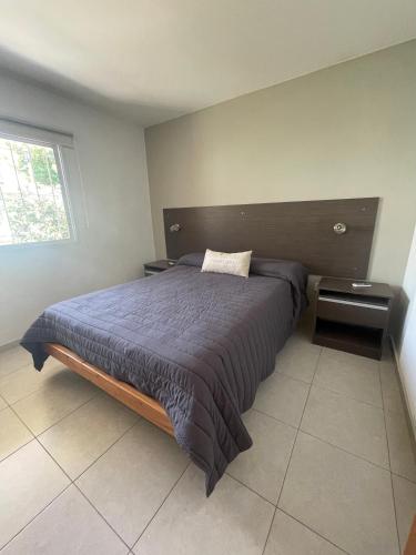 um quarto com uma cama com um edredão azul e uma janela em Brisas del Sur em Villa Carlos Paz