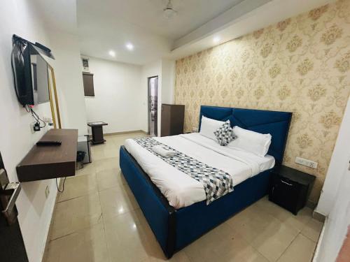 a bedroom with a blue bed and a television at Hotel Kelvish by Foxi Group in New Delhi