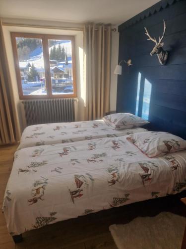 1 dormitorio con 1 cama con edredón blanco y ventana en Appartement La Duchère Le Plan-la Giettaz massif des Aravis en La Giettaz