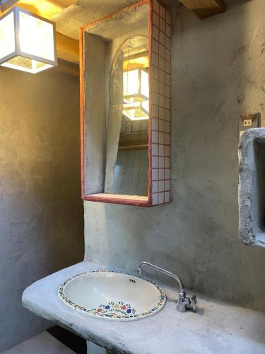 W łazience znajduje się umywalka i lustro. w obiekcie ギャラリー宿　INNAHOUSE ANDAGALLERY w mieście Murotsu