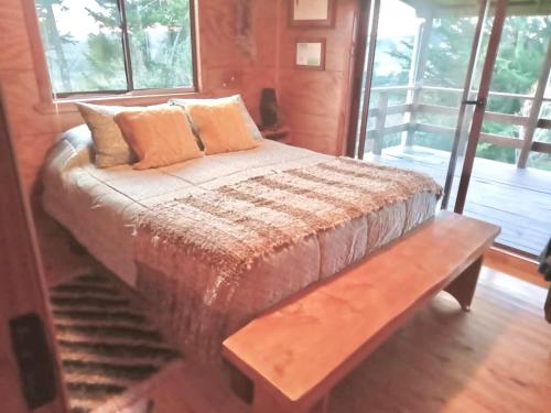 uma cama com um banco num quarto com janelas em CASA PLAYA CHAICURA em Ancud