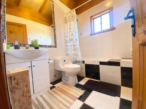 a bathroom with a white toilet and a sink at CASA PLAYA CHAICURA in Ancud